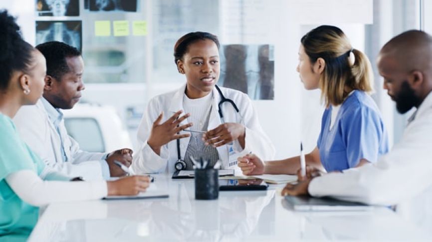 Diverse medical professionals having a discussion at a conference table in bright office