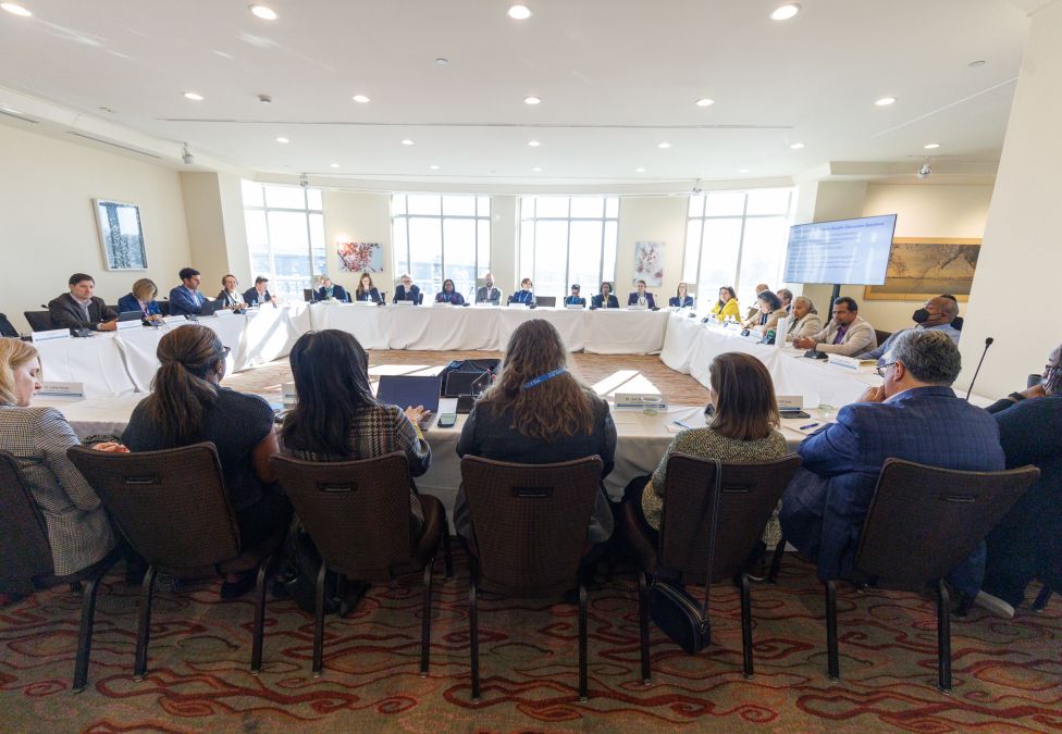 Audience seated in rows facing a panel of speakers at a conference or meeting