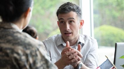 Businessman in white shirt listening attentively with clasped hands during meeting