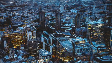 Aerial view of a dense modern city skyline illuminated at dusk.