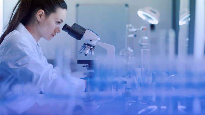 Female scientist examining samples through microscope in modern laboratory