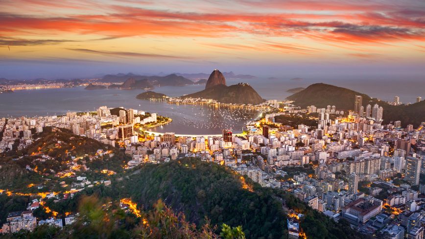 Hillside town with white buildings at sunset under colorful orange and purple sky
