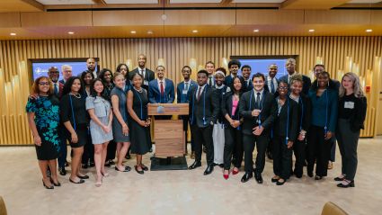 Large diverse group of professionals posing together in a modern conference room with wood paneling