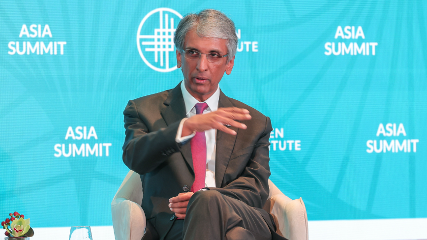 Dilhan Pillay Sandrasegara speaking at microphone with repeated "ASIA MARKET" text on blue background